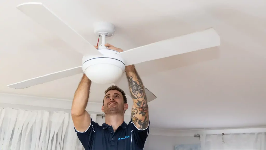 Profissional instalando um ventilador de teto branco com luz LED