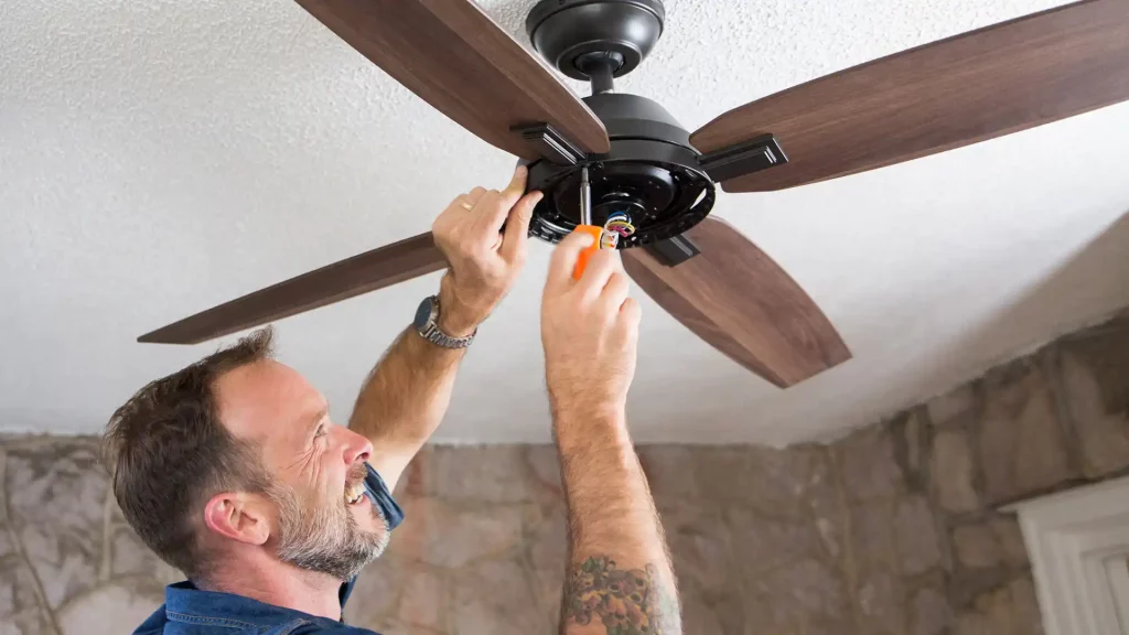 Um homem instalando um ventilador de teto amadeirado