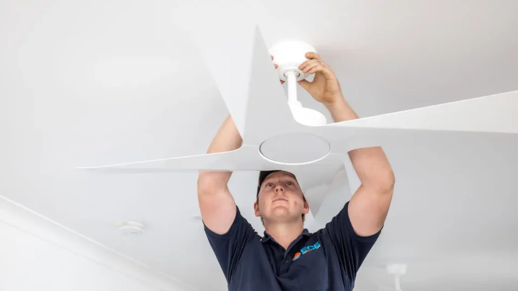 Eletricista realizando manutenção em um ventilador de teto